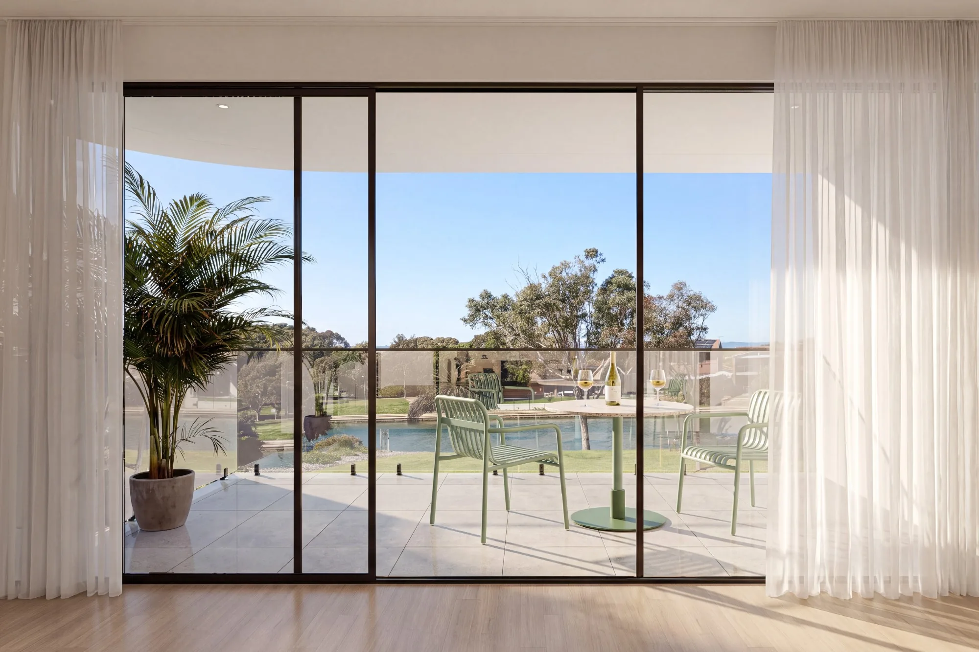 Upper-level balcony with outdoor dining overlooking parkland and water